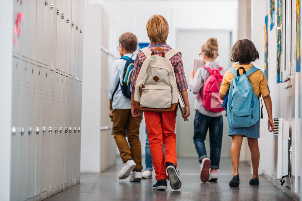 Kids walking in school with backpacks.